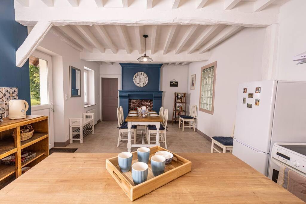 een woonkamer met een tafel en een klok aan de muur bij Le Gîte de la Melonnerie in Hardencourt-Cocherel