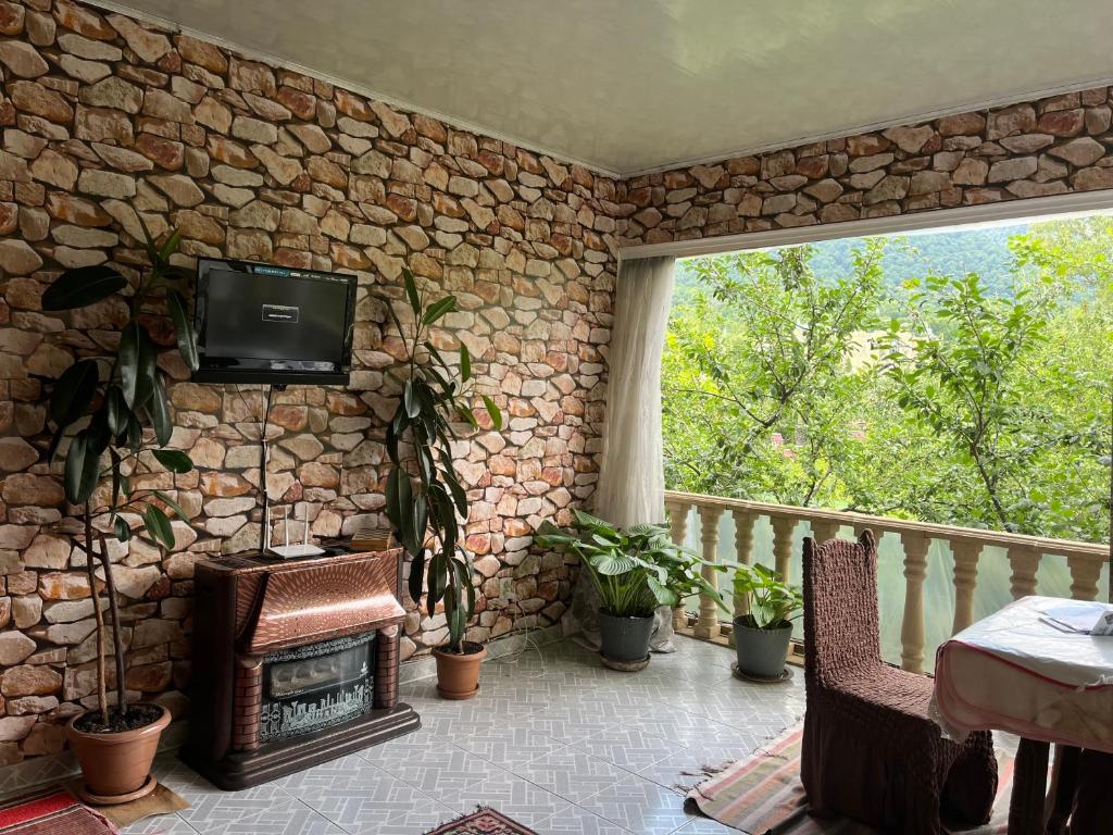 eine steinerne Veranda mit einem Kamin und einem TV in der Unterkunft Panoramic Tufandag family Apartment in Qəbələ