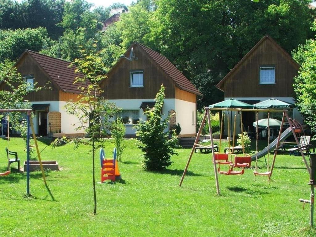 a yard with playground equipment in front of a house at Ferienhaus Steinachtal in Franken bis 5 Personen - b48519 in Marktgraitz