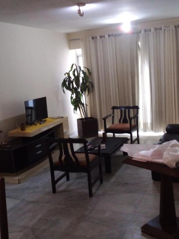 sala de estar con 2 sillas, mesa y TV en Conforto e Localização, en Recife