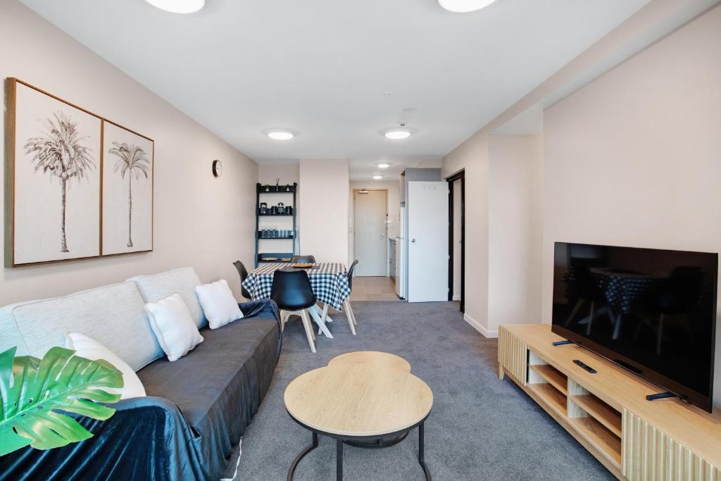 a living room with a couch and a tv at Hobson Apartment with Pool and View in Auckland