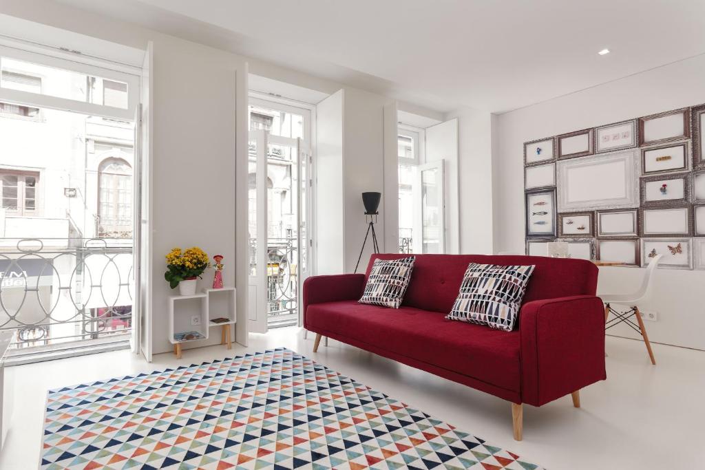 a living room with a red couch and a rug at PortoWhite city lofts in Porto