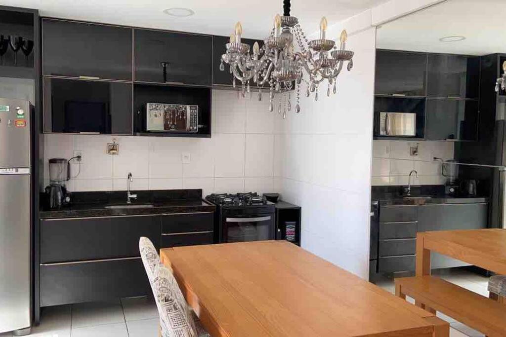 a kitchen with a wooden table and a chandelier at Completo, varanda, 800m da praia! Tranquilidade in João Pessoa