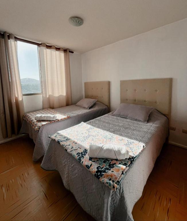 two beds in a room with a window at Apartamento amoblado 124 Ovalle in Ovalle