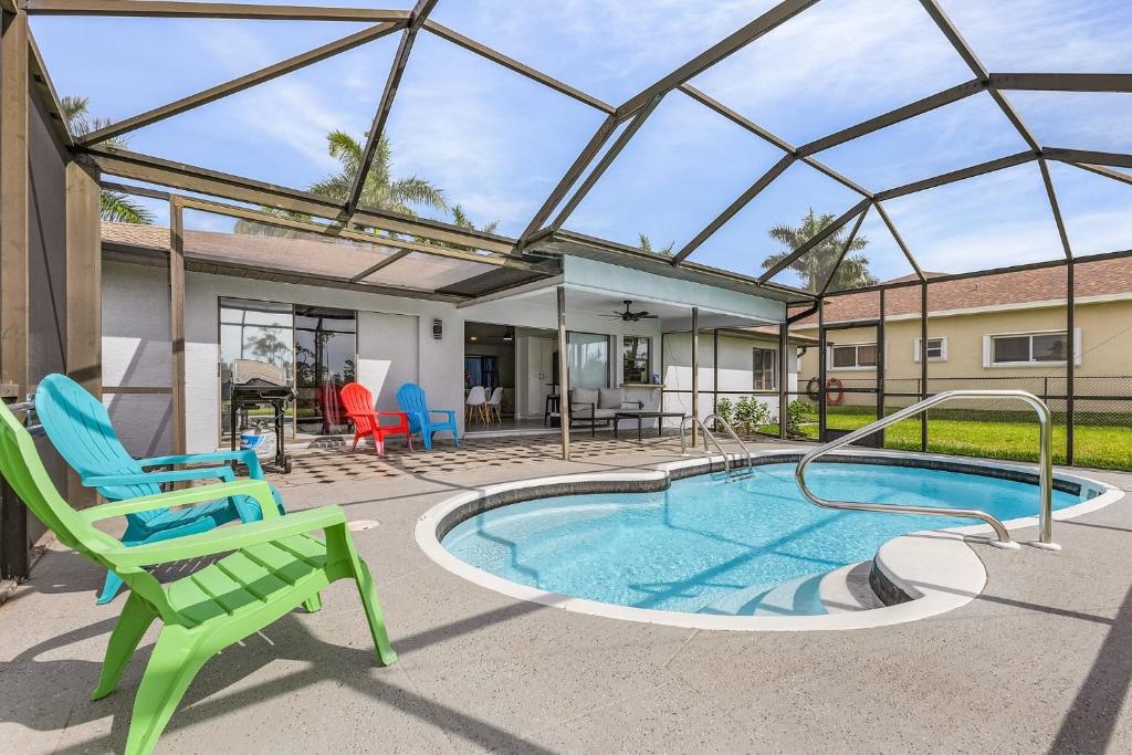 a patio with a swimming pool with a green chair and a patio at Palmetto Pines Paradise in Cape Coral