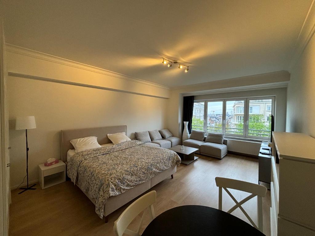 een slaapkamer met een bed, een bank en een raam bij Studio Winston Churchill in Brussel