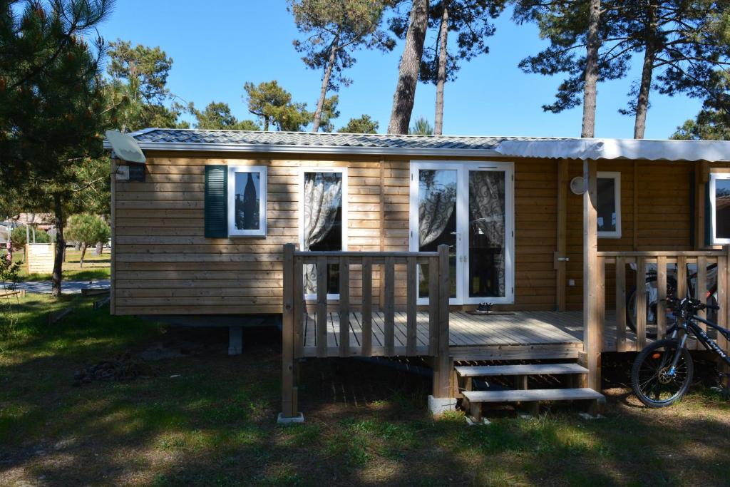 a tiny house with a porch and a bike at Hébergement dans un camping de rêve in Vendays-Montalivet