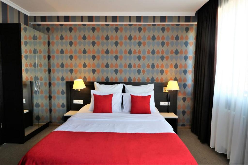 een slaapkamer met een rood bed met 2 rode kussens bij East Gate Boutique Hotel in Tbilisi City