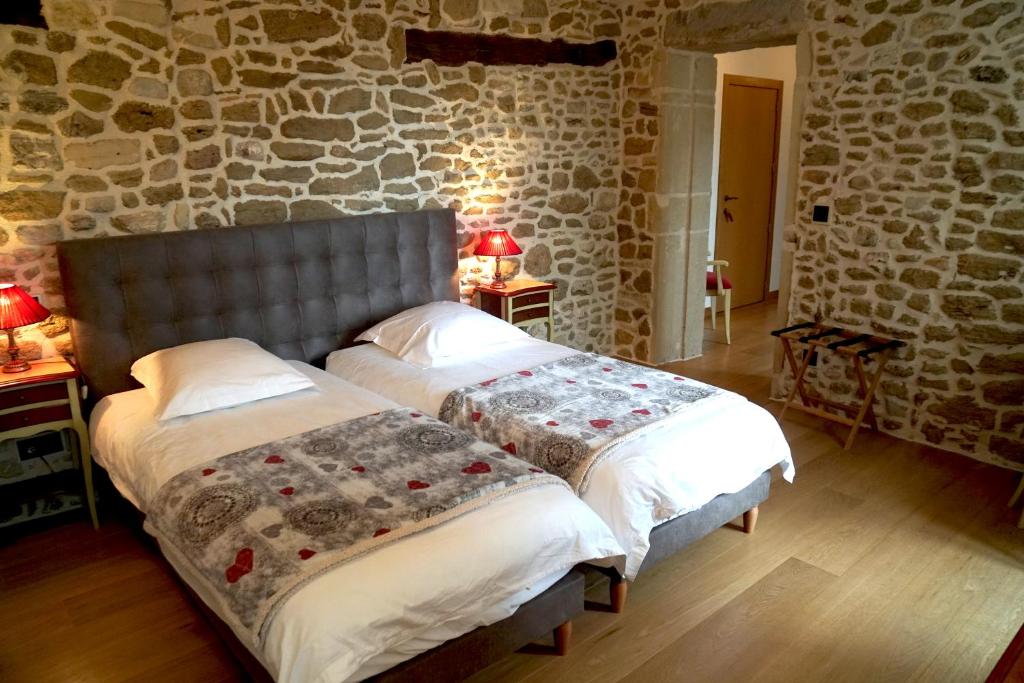 2 camas en una habitación con una pared de piedra en Domaine de la Calamande, en Grillon