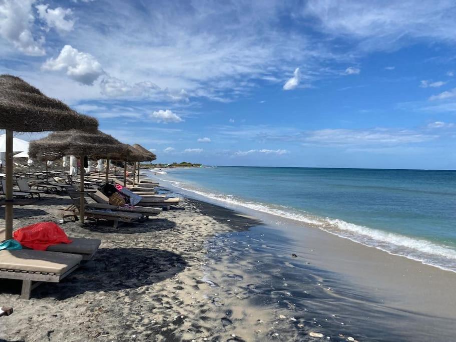 Una playa con sillas y sombrillas de paja y el océano. en Appartamento in antica casa, en Vernole