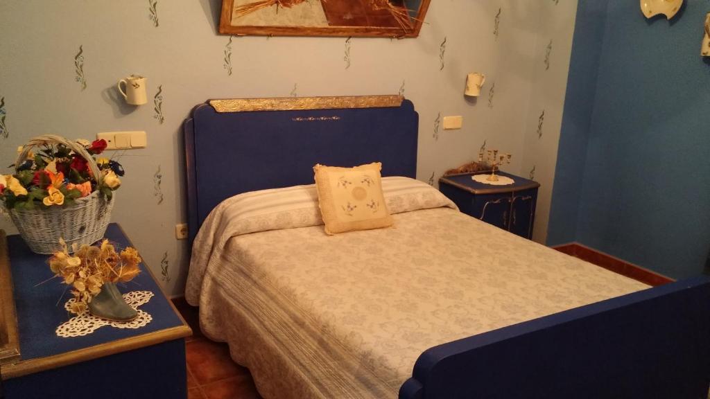 1 dormitorio con 1 cama azul y 2 mesas con flores en Hotel Restaurante Segobriga, en Villas Viejas