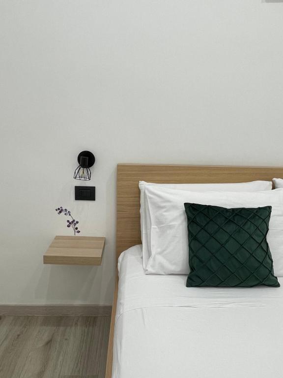 a bed with white sheets and a green pillow at Liparulo Holiday House in Massa Lubrense
