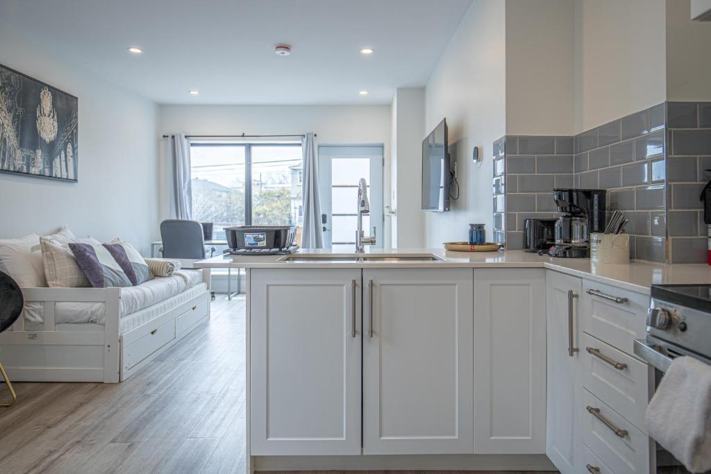 a kitchen with white cabinets and a couch in a room at Private Unit in the heart of Ottawa, 3 minutes to downtown Ottawa in Ottawa