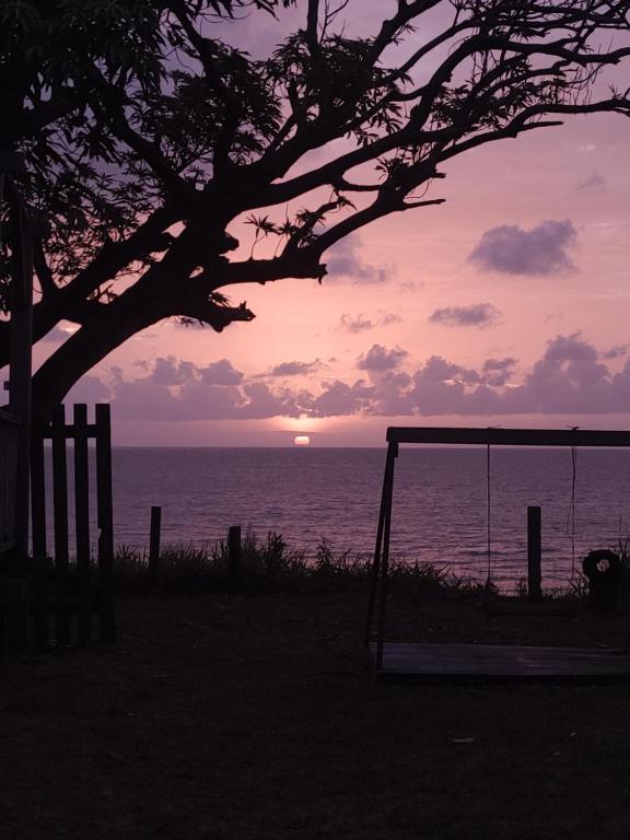 una puesta de sol sobre el océano con un columpio en Pousada Bosque dos Aruãs, en Salvaterra