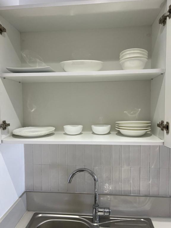 a kitchen with plates and dishes on a shelf at Appart Gab in Boumhel El Bassatine