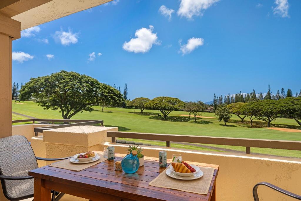 a wooden table with plates of fruit on a balcony at Kapalua Golf Villas 15T5 in Kahana