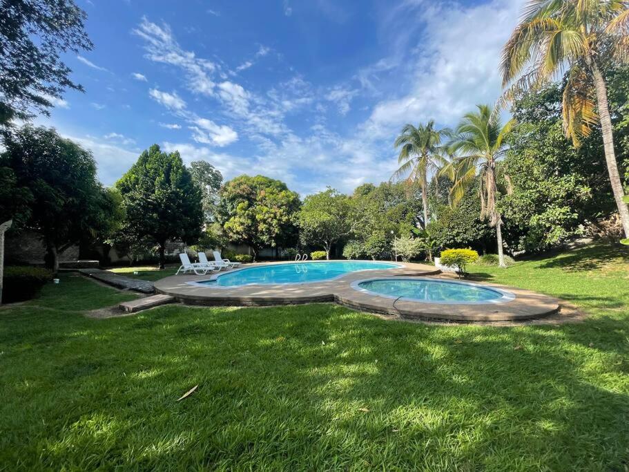 - une piscine dans une cour avec des palmiers dans l'établissement Casa vacacional con piscina privada, à Mariquita