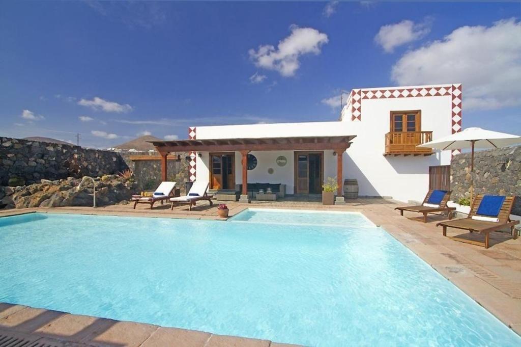 a villa with a swimming pool in front of a house at Sehr großzügig und modern eingerichtetes Ferienhaus mit privatem Pool und Sonnenterrassen im eigenen Garten in Tías