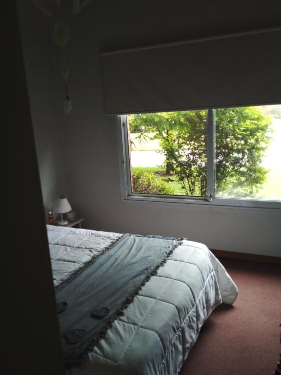 um quarto com uma cama e uma grande janela em Las Magnolias em Ingeniero Maschwitz