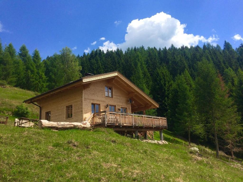 ein Haus auf einem Hügel mit einer Holzterrasse in der Unterkunft Gemütliche Berghütte mit Sauna in beeindruckender Höhenlage in Rangersdorf