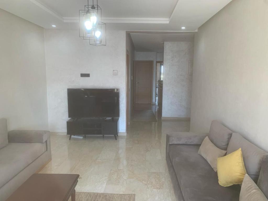 een woonkamer met een bank en een flatscreen-tv bij Agadir Bay in Agadir