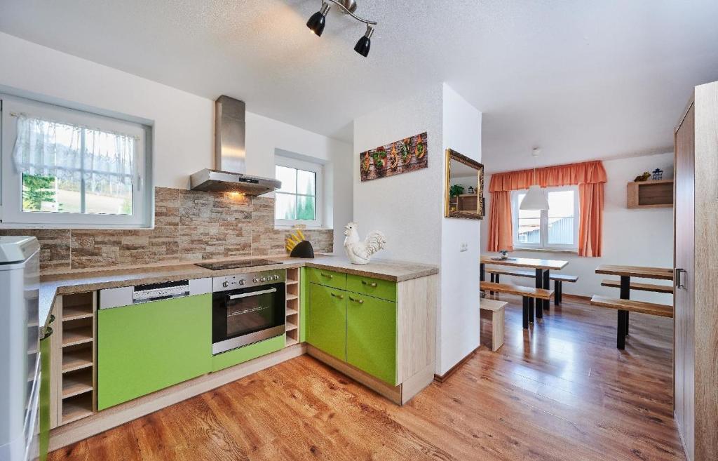 a kitchen with green cabinets and a dining room at Ferienhaus in Kollnburg mit Bergblick in Kollnburg