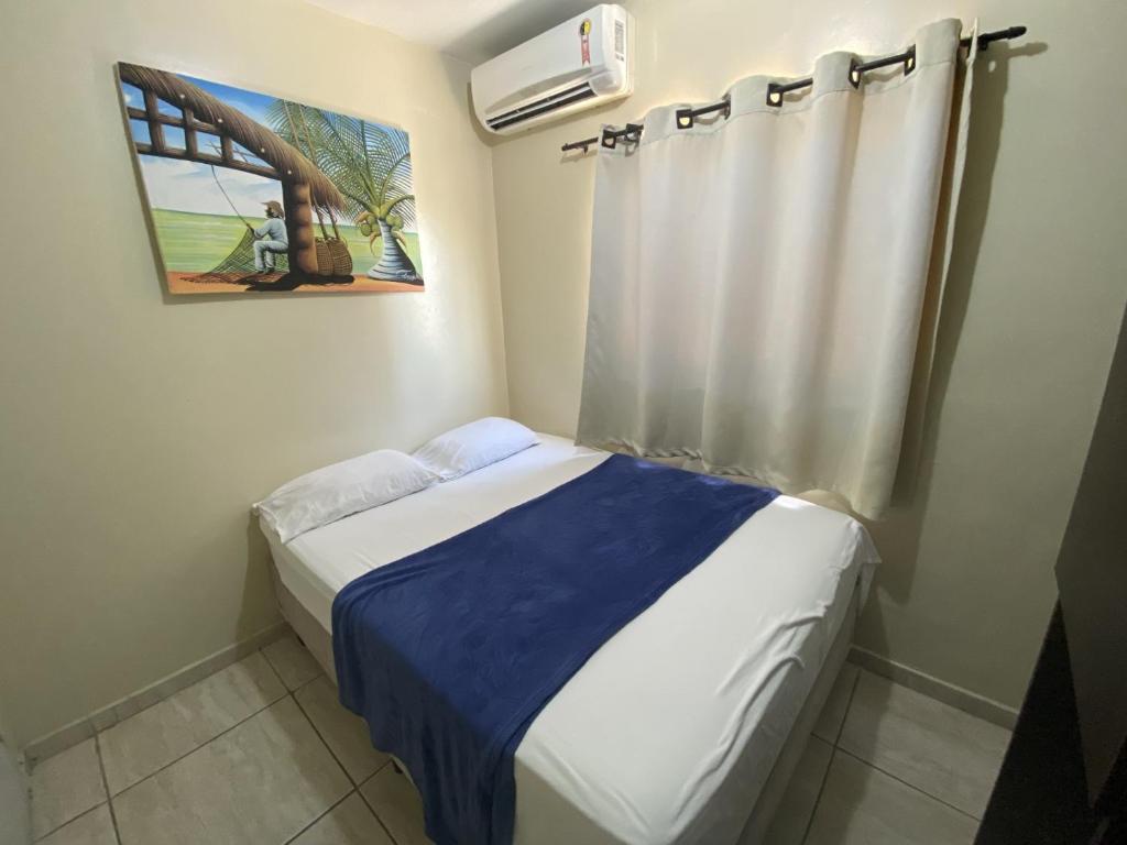 a small bedroom with a bed with a blue blanket at Hotel Pousada dos Anjos in João Pessoa