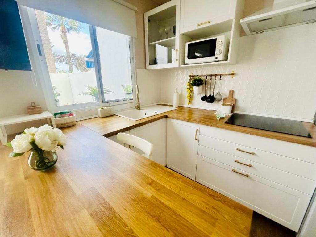 a kitchen with white cabinets and a vase of flowers at Precioso bungalow residencial Santa Marta in Costa Del Silencio