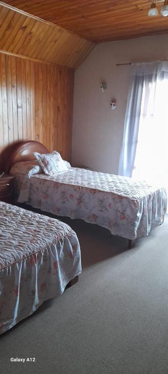 1 dormitorio con 2 camas y ventana en chaleth en Trelew