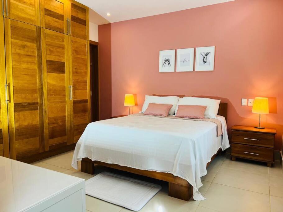 1 dormitorio con 1 cama blanca y paredes rosas en Acogedor apartamento en playa Las Ballenas, en Las Terrenas