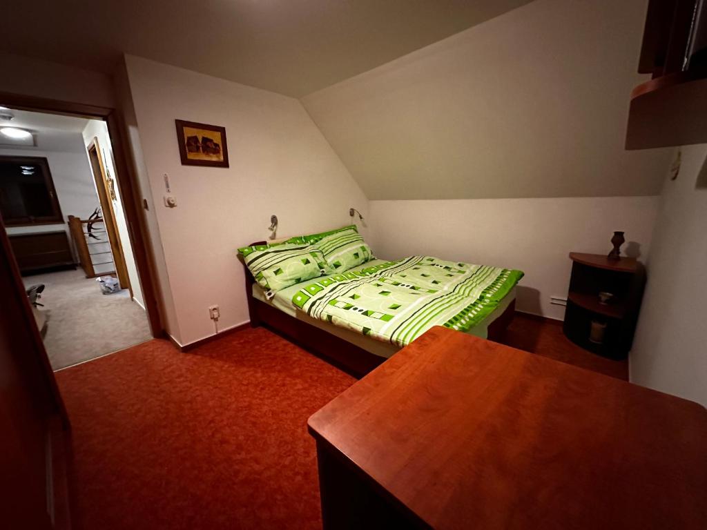 a bedroom with a bed with a green comforter at Chata u cestaře in Loučná pod Klínovcem