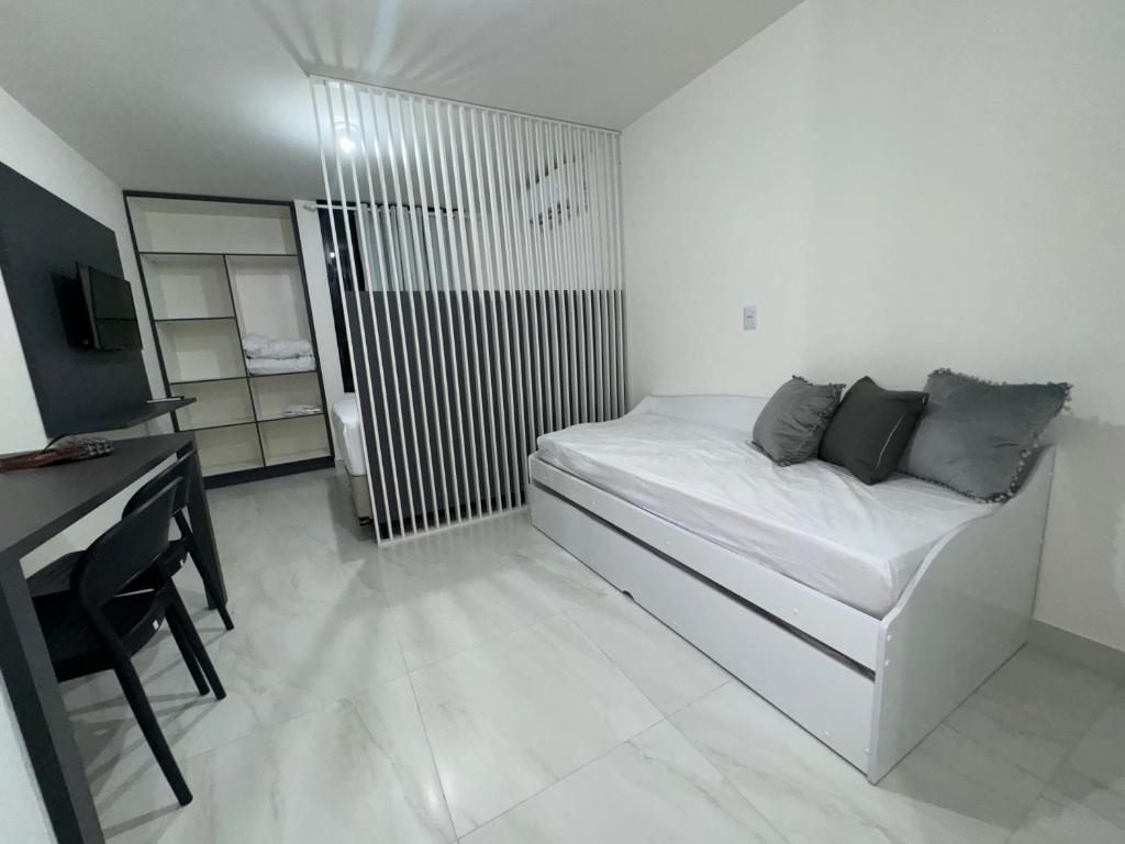 a white room with a bed and a desk at Flat a 400 metros da praia!, ótima localização. in Cabedelo