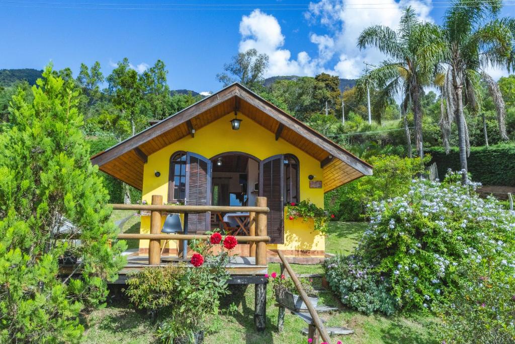a small yellow house with a porch at Chalés Pedra do Baú in São Bento do Sapucaí