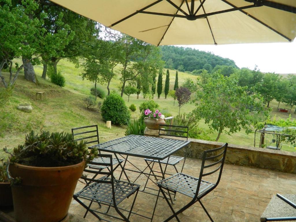 un patio con mesa, sillas y sombrilla en Ferienwohnung für 4 Personen ca 80 qm in Castiglione d'Orcia, Toskana Provinz Siena, en Campiglia dʼOrcia
