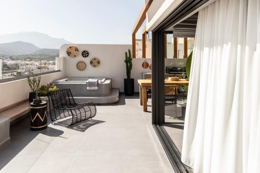 a living room with a couch and a tub on a balcony at The sand City apartment with Outdoor Hot Tub in Agios Nikolaos