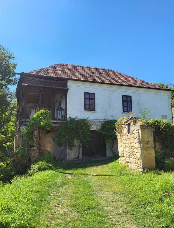 uma velha casa de pedra num quintal relvado em Country house pivnica Milic Rogljevo em Rogljevo