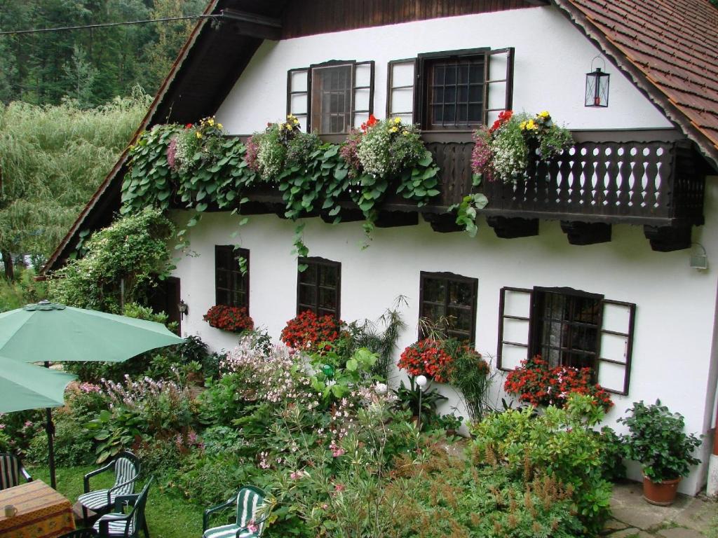 Una casa blanca con flores a un lado. en Komfortables Landhaus mit Gartengrundstück und Naturbadeteich direkt am Wald und verkehrsbegünstigt für Ausflüge, en Rettenberg