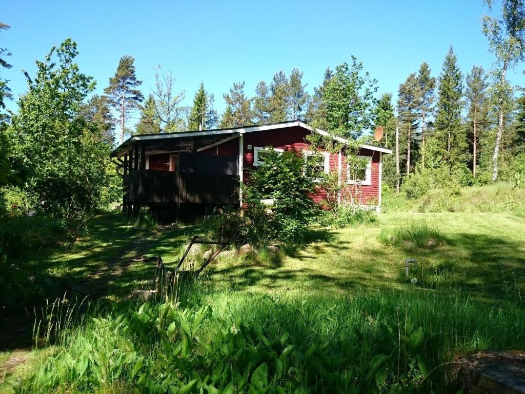 uma pequena casa vermelha no meio de um campo em Typisches Holzhaus mit überdachter Terrasse auf weitläufigen Grundstück in einem Waldgebiet am See em Hallaryd