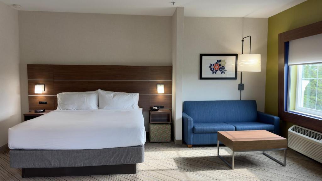 a hotel room with a bed and a blue couch at Holiday Inn Express Hotel & Suites Marina, an IHG Hotel in Marina