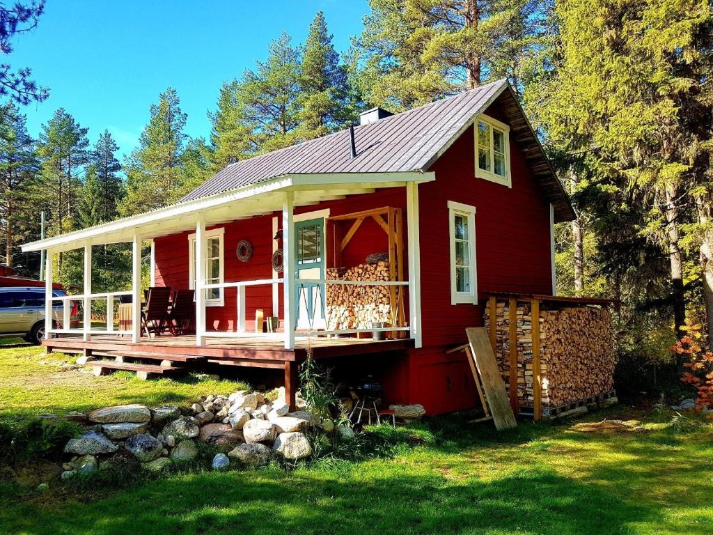 una casa roja con porche en el césped en Charmantes Ferienhaus in der Wildnis Lapplands en Blattnicksele