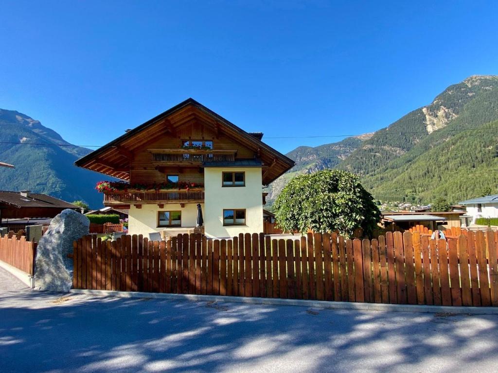 a wooden fence in front of a house with mountains at Großzügiges Appartment mit Balkon im Herzen von Tirol in Umhausen