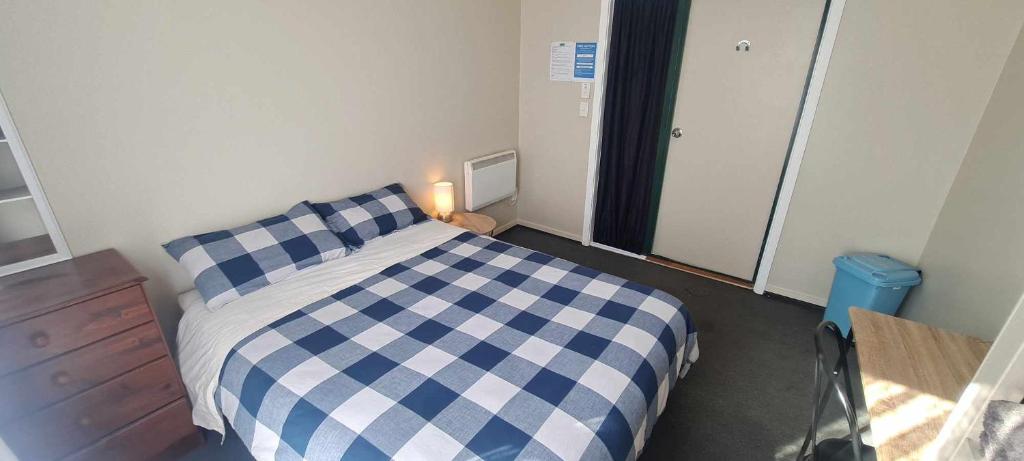 布倫海姆的住宿－Tō Tātou Kainga，卧室配有蓝色和白色的格子床