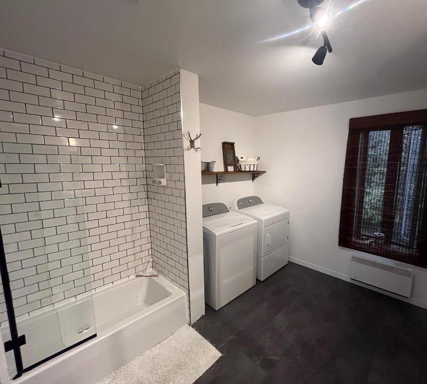 a bathroom with a tub and a washer and dryer at Gite - La ruée vers l'orge in Trois-Rivières