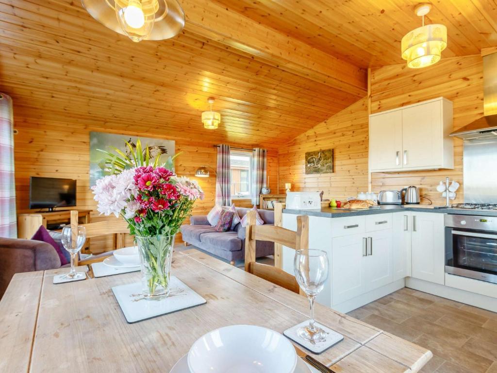 cocina y sala de estar con una mesa con flores en 2 Bed in Loch Leven 82297, en Kinross
