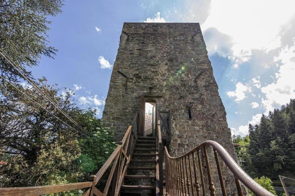 una escalera que conduce a una torre de piedra con una puerta en Mittelalterlicher Turm in Pratovecchio mit Panoramaterrasse- ideal für einen romantischen Urlaub, en Stia