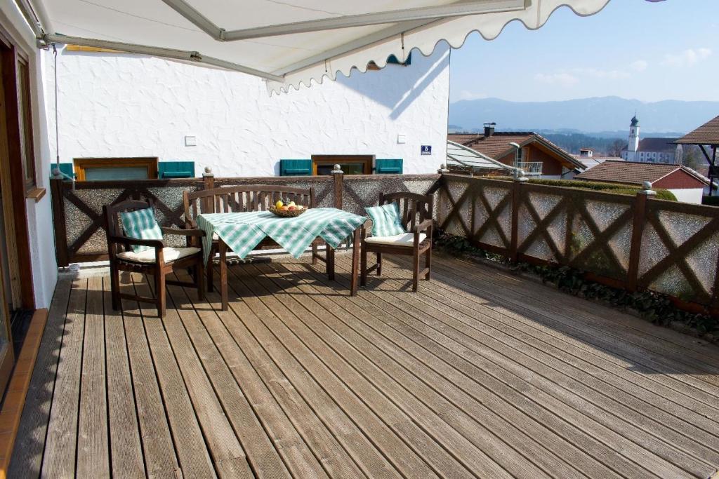 a table and chairs on a wooden deck at Schönes Ferienhaus in Lechbruck Am See mit Großer Terrasse und Bergblick in Lechbruck