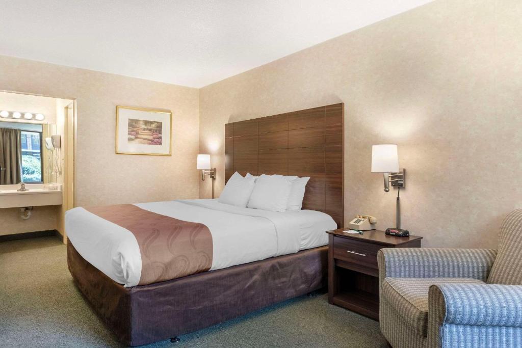 a hotel room with a large bed and two chairs at Quality Inn Vienna - Tysons Corner in Tysons Corner