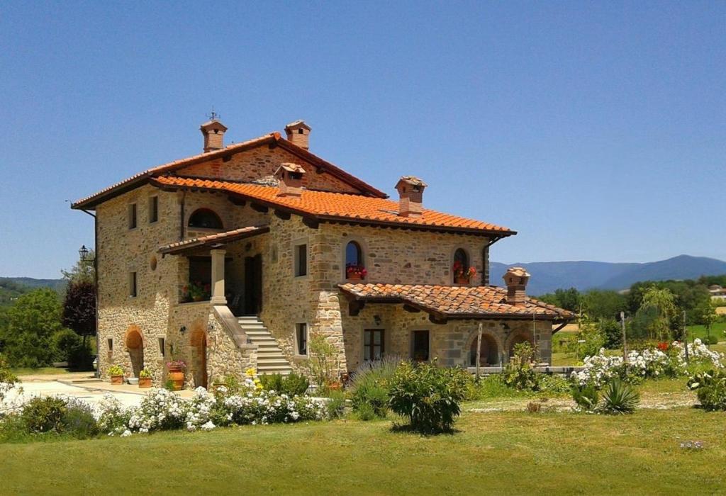 een groot stenen huis met een oranje dak bij Ferienwohnung in einem toskanischen Landhaus, mit privater Panoramaterrasse in Poppi