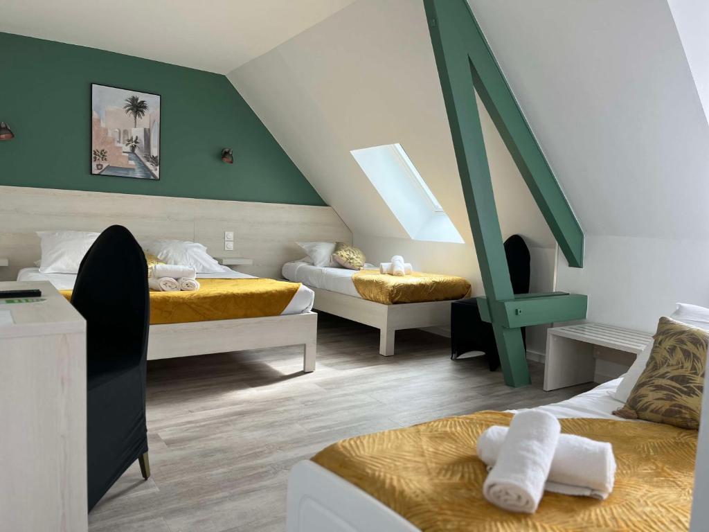 a bedroom with two beds and a green wall at Brit Hotel Du Dauphin L'Aigle in LʼAigle