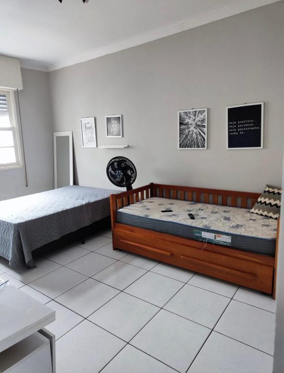a bedroom with two beds on a tiled floor at Pé na Areia em Santos in Santos